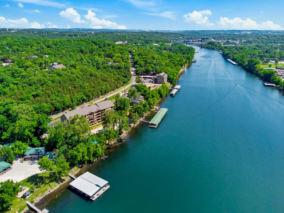 A picturesque view of the river bordered by lush greenery and buildings along the shore. The tranquil waterway invites boating, fishing, and serene river walks, with ample space for picnicking and observing local wildlife. The image captures the spirit of outdoor adventure and peaceful riverside experiences.