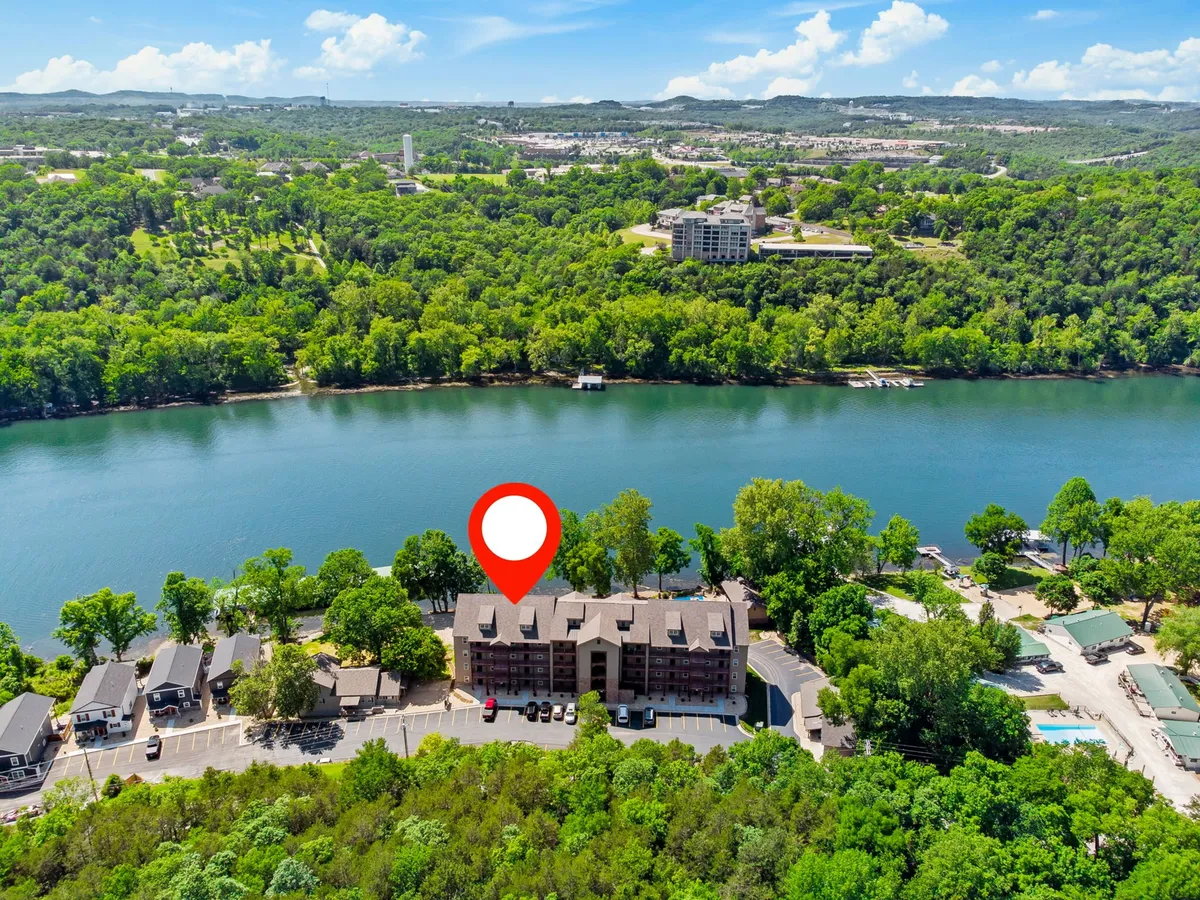 An exterior shot showcasing the river, surrounding greenery, buildings, a pool area, and a parking lot. The inviting outdoor amenities and access to nature are evident, with the river as a central focus and opportunities for swimming, boating, and relaxing by the water.