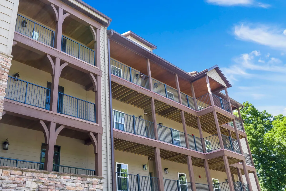 A multi-level exterior shot featuring three tiers of balconies with wooden beams and a stone base. The balconies overlook the water, suggesting intimate settings for relaxation and socializing while taking in scenic views.