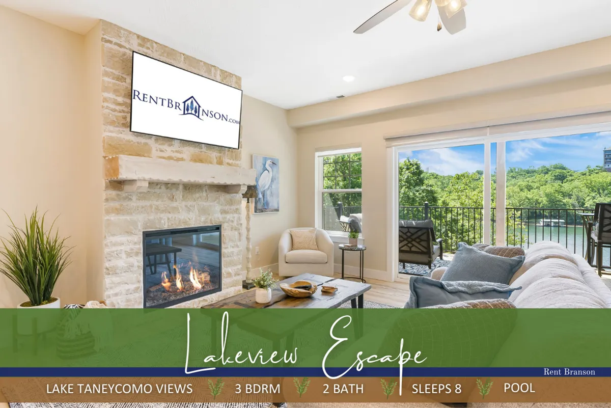 A spacious living area featuring a cozy fireplace, large windows that let in abundant natural light, comfortable seating, and a television. The windows offer beautiful views of Lake Taneycomo, creating a relaxing and inviting environment.